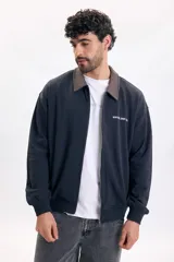 Campera azul oscuro de felpa con cierre frontal, cuello camisero en contraste de color marrón, puños y ruedo elásticos, y pequeños estampados con texto en el pecho.