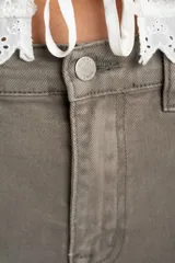 Jean de corte wide leg y tiro medio, en color gris topo. Presenta un diseño de pierna ancha con ruedo desflecado y cierre frontal con botón y cremallera.