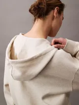 Buzo con capucha y cierre frontal completo, color beige jaspeado, confeccionado en suave fleece de mezcla de algodón y poliéster. Presenta bolsillos laterales y el logo Archive de Calvin Klein bordado en el pecho.