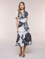 Vestido midi de seda fría con estampado floral en blanco y negro, cuello en V y mangas cortas acampanadas. Cuenta con cintura elastizada y falda evasé con volado en el ruedo.