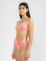 Conjunto de bikini de lycra estampada con motivos abstractos en tonos rosados y anaranjados. El corpiño es de corte triangular con tirantes finos y la bombacha es de tiro alto.