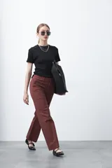 Pantalón de mujer color terracota/marrón rojizo, de tiro alto y corte recto/ancho, con costuras frontales marcadas.