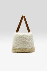 Bolso estilo tote con cuerpo de piel sintética afelpada en color blanco en la parte superior y marrón claro en la base, con asas de mano de cinta marrón.