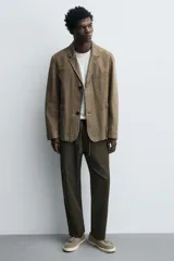 Mocasín casual de piel con acabado de serraje en color gris, con detalle de borlas en el empeine y suela plana a contraste en color beige.