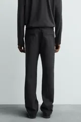 Pantalón chino de corte oversized confeccionado en tejido de algodón con estructura twill. Presenta bolsillos frontales, bolsillos traseros de vivo y cierre frontal con cremallera y gancho metálico oculto.