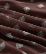 Blusa tipo bata confeccionada en tule con forro interior, escote en V, mangas cortas con detalle de lazo y cintura fruncida. Presenta un estampado geométrico tipo pañuelo.