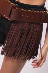 Falda de cuero sintético color marrón con flecos largos y cinto ancho con hebilla cuadrada.