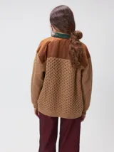 Campera tejida de punto grueso en color beige, con cuello en contraste color verde. Presenta cierre frontal con botones, bolsillos delanteros con apliques en nylon color marrón y bordado decorativo, y forro interno de nylon.