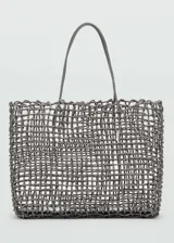 Bolso shopper grande de estilo trenzado, color gris, con dos asas superiores y detalle de charm metálico colgante.