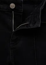 Pantalón tipo capri de denim negro con corte skinny, tiro medio, cierre de cremallera y botón, y costuras decorativas verticales en el frente.