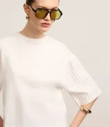 Remera boxy de mangas cortas amplias, color blanco, confeccionada en algodón, con cuello redondo y rayas verticales en las mangas y en la espalda.