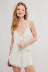 Conjunto de dos piezas de color blanco, confeccionado en viscosa fluida y liviana. Incluye una musculosa con escote en V, detalles de encaje y tirantes finos regulables, y un short con cintura elastizada y bordes de puntilla.