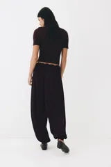 Pantalón globo de corte relajado en punto de crepé, color negro. Cuenta con cintura elástica de tiro bajo con cordón ajustable y piernas globo con puños anchos.
