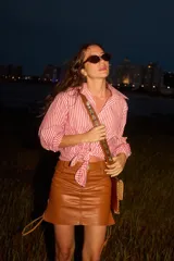 Camisa de corte clásico con estampado de rayas verticales rojas y blancas, cuello camisero, mangas largas con puños y cierre frontal de botones.