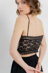 Top crop negro de cuero ecológico con espalda de encaje floral nude, tirantes finos y corte entallado.