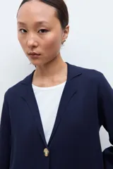 Sacón azul marino de corte largo, con cuello solapa, cierre frontal de dos botones dorados y bolsillos de parche.