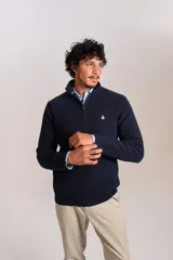 Sweater de punto acanalado color azul marino, con cuello alto y cierre frontal parcial. Presenta el logo de la marca bordado en el pecho y puños con terminación elástica.