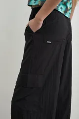 Pantalón estilo cargo color negro, confeccionado en tela avión, con cintura elastizada ajustable mediante cordón y puños regulables en los tobillos con tiras para ajustar.