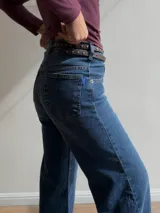 Pantalón de jean estilo wide leg con tiro alto, corte recto y amplio desde la cadera hasta el ruedo. Presenta un lavado azul clásico con sutiles detalles de textura.