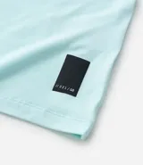 Remera deportiva de hombre con tecnología dry fit, cuello redondo y manga corta. Presenta un diseño liso en color beige con una pequeña etiqueta decorativa en el dobladillo.