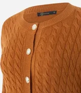 Cárdigan de punto trenzado color marrón, con cuello redondo, manga larga y cierre frontal con botones metálicos. Presenta puños y ruedo acanalados.