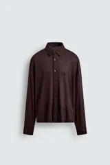 Camisa de manga larga color marrón oscuro, con cuello solapa y cierre frontal de botonadura. El tejido es semitransparente y presenta una textura jacquard.