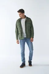 Campera de gabardina verde militar con capucha desmontable y ajustable, cierre frontal con cremallera y múltiples bolsillos con solapa.