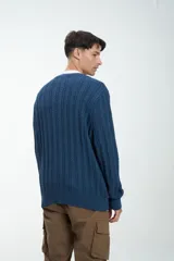 Sweater color gris claro de punto trenzado, con cuello redondo y mangas largas.