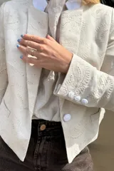 Blazer de lino color crema con bordado a tono en toda la prenda. Diseño sastrero con cuello solapa y cierre frontal con botones forrados.