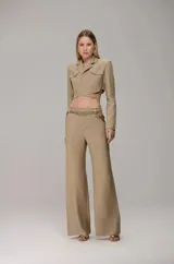 Conjunto de sastrería compuesto por un blazer corto tipo crop con diseño cruzado, solapas clásicas y bolsillos frontales, y un pantalón de vestir de corte recto. El diseño presenta una estética estructurada y moderna.