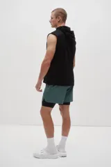 Short deportivo de doble capa color verde con calzas cortas negras incorporadas en el interior. Cuenta con tecnología DryMove™, cintura elástica negra con cordón ajustable, bolsillos laterales y aberturas en el bajo.