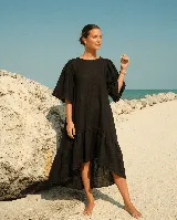 Vestido largo de lino color beige, con mangas abullonadas y volado inferior asimétrico, más largo en la parte trasera.