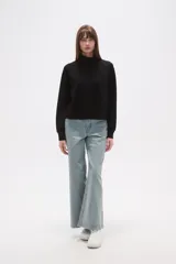 Buzo de manga larga color negro, con cuello alto tipo mock neck y corte holgado. Presenta costuras tipo raglán en los hombros.