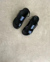 Sandalia negra de plataforma gruesa, con dos tiras anchas sobre el empeine y tira ajustable en el talón.