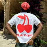 Camiseta blanca de manga corta y corte oversize, con estampa en la espalda de dos cerezas rojas con forma de corazón y el logo de la marca en rojo.