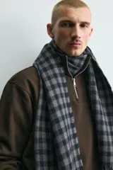 Bufanda de tejido suave con diseño de cuadros vichy en tonos gris y azul marino, terminada con flecos en los extremos.