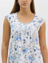 Pijama compuesto por remera sin mangas con escote redondo, botones frontales y detalle de puntilla, acompañado de un pantalón capri con cintura elástica. Presenta un estampado floral en tonos rosados sobre base gris.