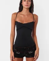 Microshort de jean negro con proceso de sobre teñido y lavado, tiro bajo y corte ajustado. Presenta costuras rojas en toda la prenda, cartera con cierre metálico, presillas largas y detalle de avío en recorte de canesú.