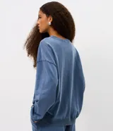 Buzo cerrado de fleece color azul, con cuello redondo, mangas largas, puños y ruedo ajustados. Presenta estampa frontal con la palabra "LONDON" en letras blancas con borde oscuro.