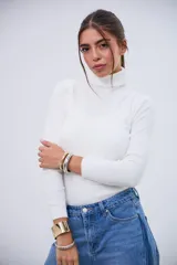 Polera blanca de cuello alto, manga larga y tejido acanalado.