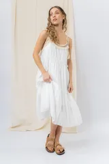 Vestido largo blanco de algodón con escote en V, breteles finos regulables con lazo y borlas, y detalle de tejido artesanal en el escote.