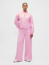 Buzo deportivo de color rosado con cuello alto y medio cierre frontal. Presenta el logo de la marca Gap 1969 bordado en el pecho junto a un emblema circular. Posee mangas largas con puños elásticos y un corte holgado.