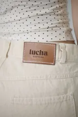 Bermuda de denim azul claro, de tiro medio y largo a la rodilla, con calce relajado y silueta amplia. Cuenta con bolsillos delanteros y traseros, y cierre frontal con botón y cremallera.