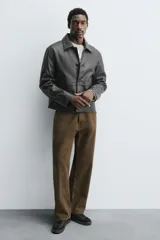 Zapatilla deportiva de estilo retro, color negro, con parte superior fabricada en combinación de piezas de cuero liso y gamuza perforada. Presenta una suela de goma en color marrón oscuro o ahumado en contraste.