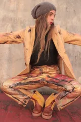 Pantalón de cuero color beige con estampado artístico en tonos rojos, marrones y negros.