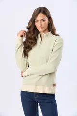 Buzo tejido combinado de color verde claro, con cuello alto, cierre frontal parcial y detalles en tono beige en el cuello, los puños y el ruedo. Cuenta con un aplique de cuero con logo en la parte inferior.