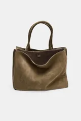 Bolso de hombro formato maxi city confeccionado en piel de gamuza color marrón. Cuenta con doble asa de hombro, doble compartimento interior y cierre mediante clip metálico y cremallera.