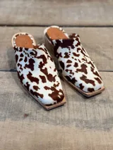 Zuecos con estampado de vaca en tonos marrones y blancos, con punta cuadrada y suela de madera.