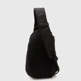 Mochila tipo bandolera de un solo hombro, color tostado, con correas ajustables negras y cierre frontal.