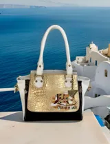 Cartera de cuero hecha a mano de la marca Carolina De Cunto, modelo Mila, con diseño tricolor en blanco, negro y detalle central dorado texturizado con arte pintado a mano. Cuenta con asas superiores blancas y herrajes metálicos.
